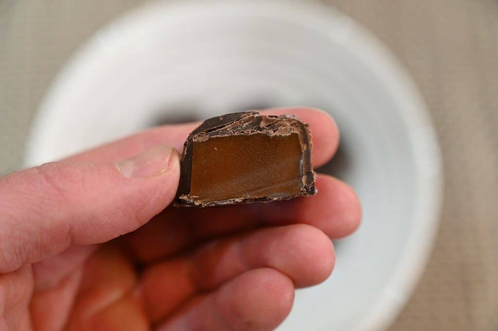 Closeup image of one Costco Sanders Dark Chocolate Sea Salt Caramel cut in half so you can see the caramel inside