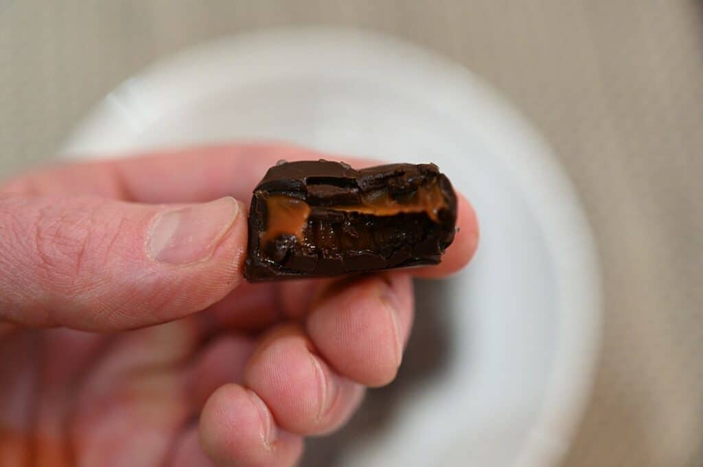 Closeup image of one Costco Sanders Dark Chocolate Sea Salt Caramel with a bite taken out of it