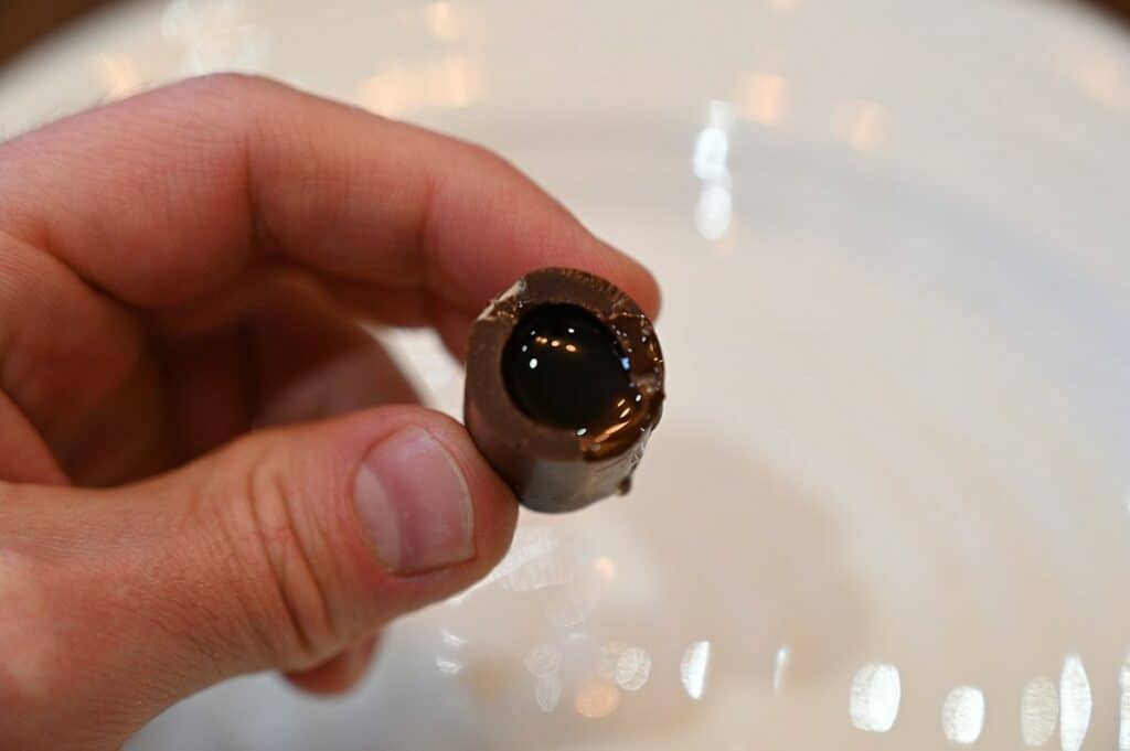 A single chocolate with a bite taken out of it to show the liquor inside.