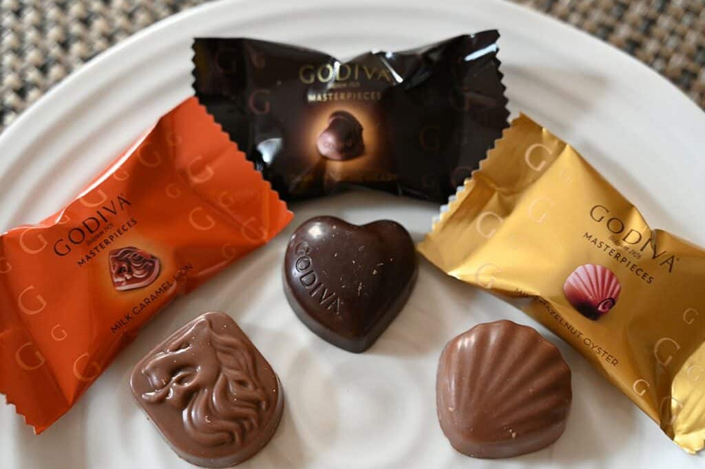 Costco Godiva Masterpieces Chocolates image of three different kinds of chocolates unwrapped and on a plate, caramel milk chocolate, dark chocolate ganache and hazelnut. 