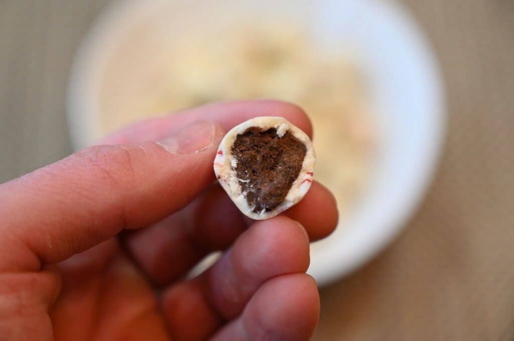 Image of one Trufettes De France Peppermint White Chocolate Bite with a bite taken out so you can see what the inside looks like 