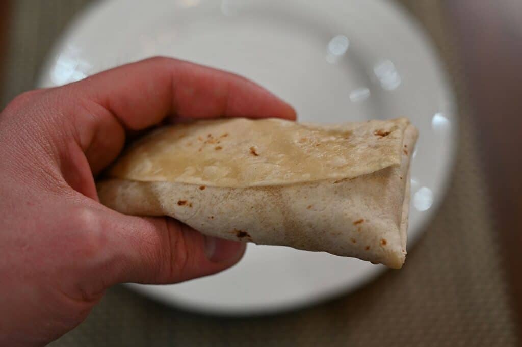 A top-down photo of the Costco El Monterey Breakfast Wrap cooked and holding it in hand