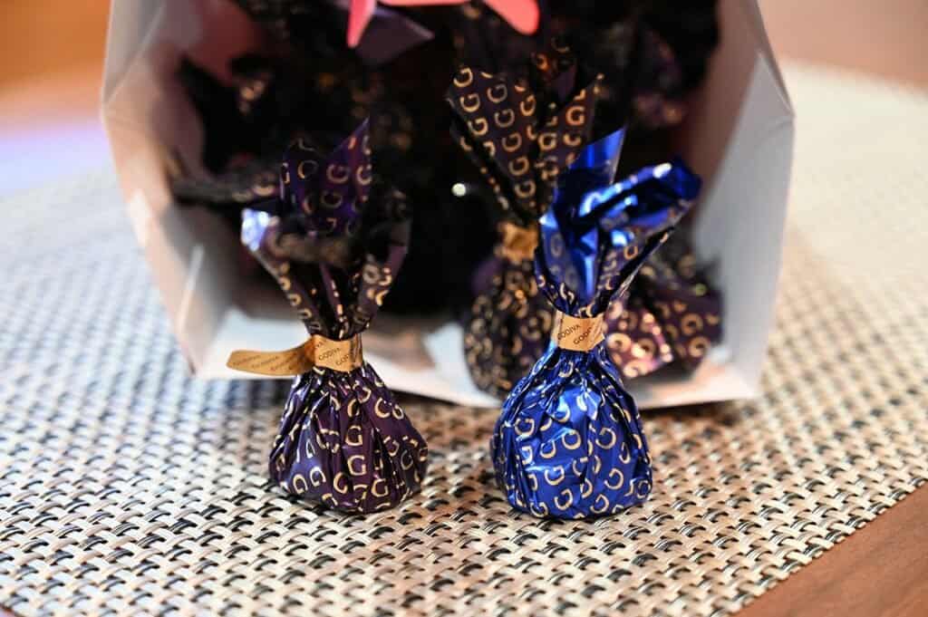 Image of the Costco Godiva Chocolate Domes, both flavors, dark chocolate and milk chocolate wrapped and sitting on the table, spilling out from the box. 