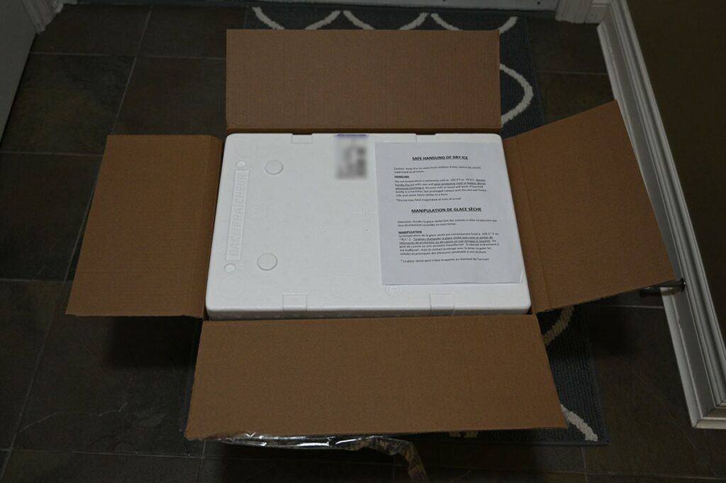 Image of the shipment box of the Costco Seacore Frozen Lobster Tails with the dry ice safe handling instruction paper on top of the box. 