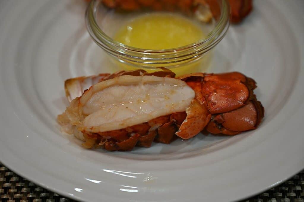 Side image of one cooked Costco Seacore Frozen Lobster Tail with a side of garlic butter on the plate