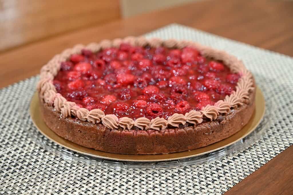 Side close up image of the Costco Kirkland Signature Chocolate Raspberry Tart with the container lid off so you can see the tart.