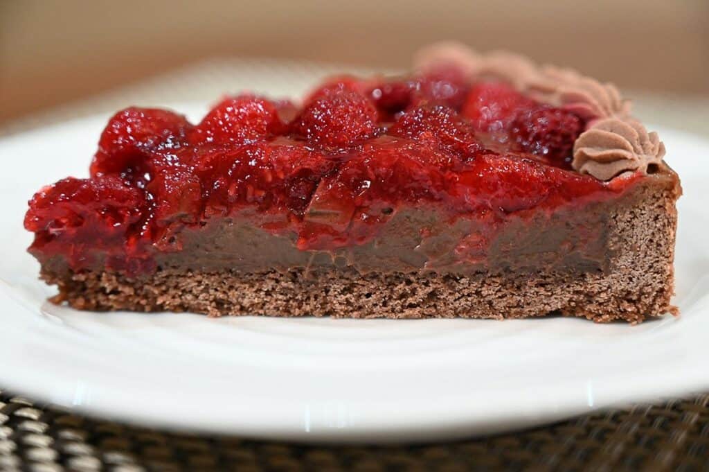 Side close up image of one slice of the Costco Kirkland Signature Chocolate Raspberry Tart with the so you can see the distinct layers. 