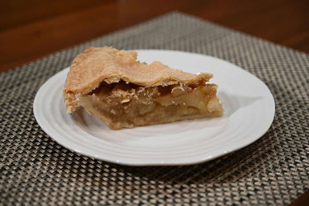 Side image of one slice of Costco Kirkland Signature Homestyle Apple Pie on a white plate.