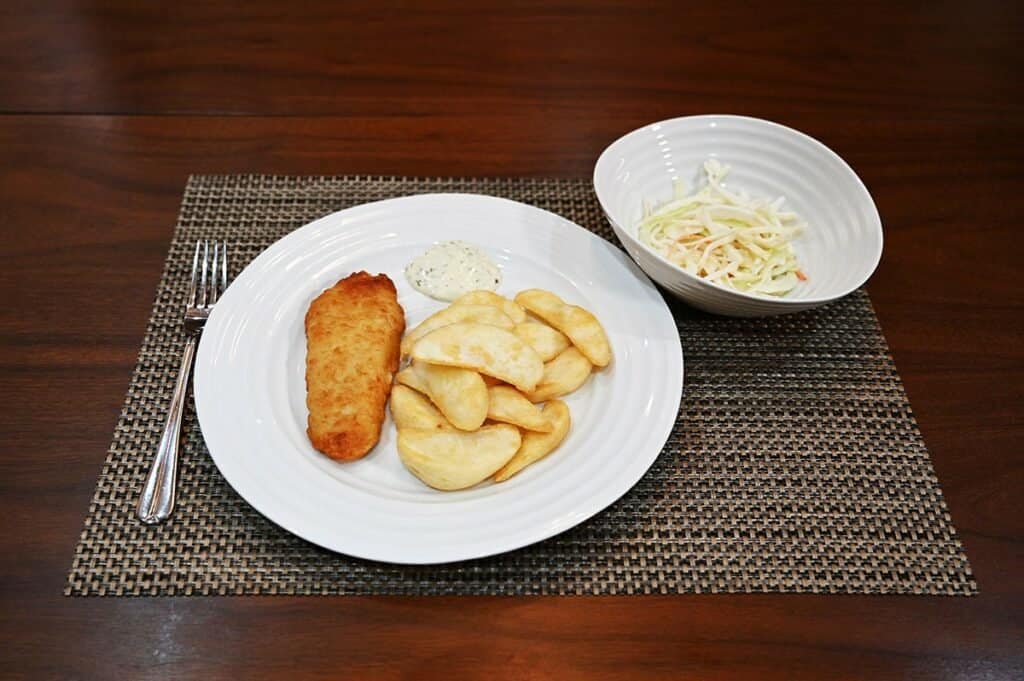 Costco Kirkland Signature Fish & Chips Meal Kit cooked and plated on white plate with a bowl of slaw on the side in a white bowl