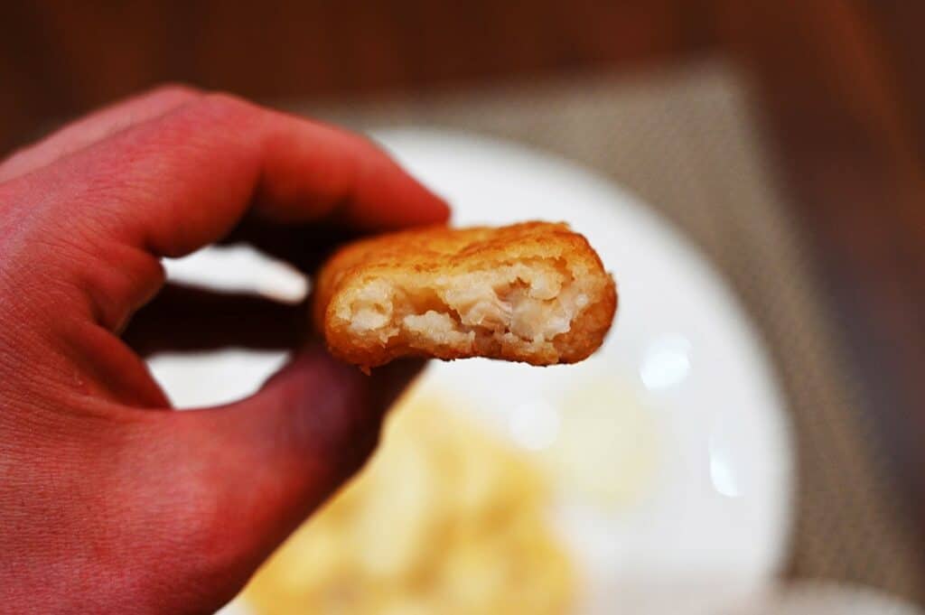 Costco Kirkland Signature Fish &  Chips Meal Kit up close image of a piece of fish with a bite taken out of so you can see the middle of the fish