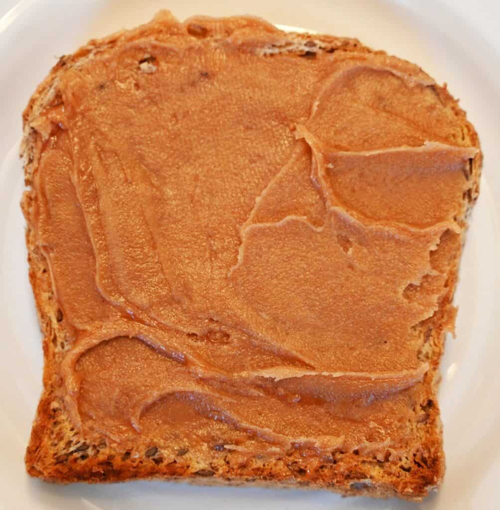 Costco Smucker's Goober spread onto a piece of a toast on a white plate. 