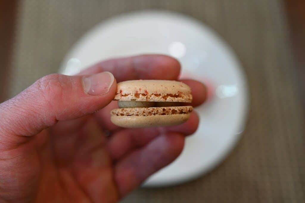 Sideview closeup image of one Vanilla Costco Le Bon Patisserie Heart Shaped Macaron so you can see the filling. 