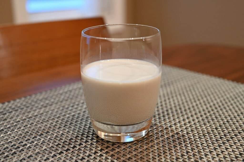 A glass of poured Costco Kirkland Signature Organic Oat Beverage.