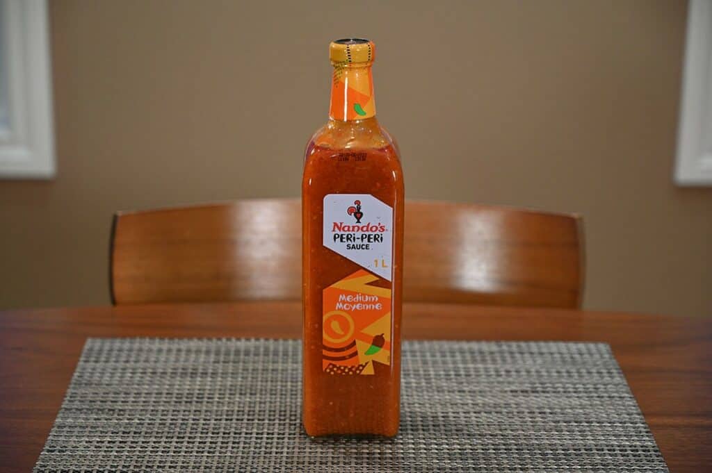 Costco Nando's Peri-Peri Sauce bottle sitting on a grey placemat on a table 