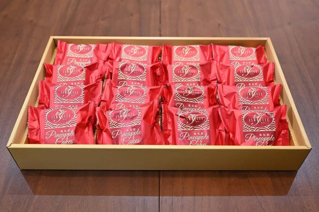 Costco Isabelle Pineapple Cake box with lid off on a brown table so you see the individually wrapped cakes in the box. 