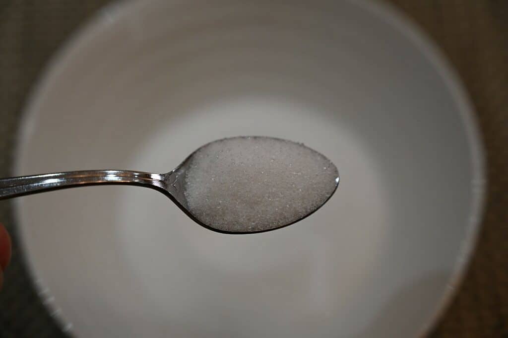 Costco Volupta Erythritol & Monk Fruit Sweetener on a spoon with bowl in background close up image.