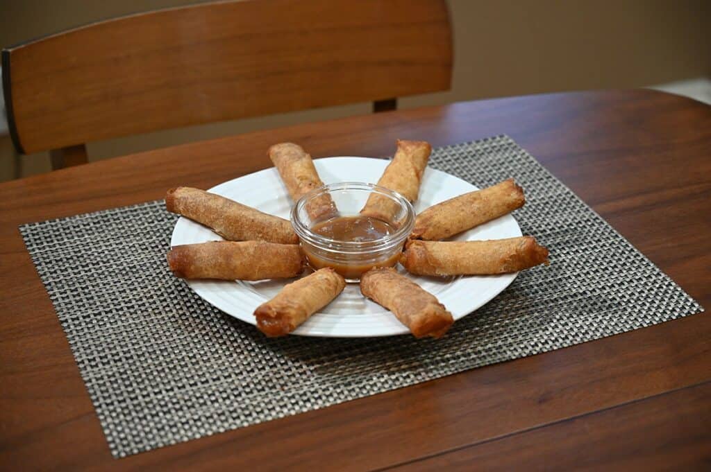 Side image of Costco Summ! Apple Pie Rolls served on a white plate with caramel dipping sauce in the middle. 