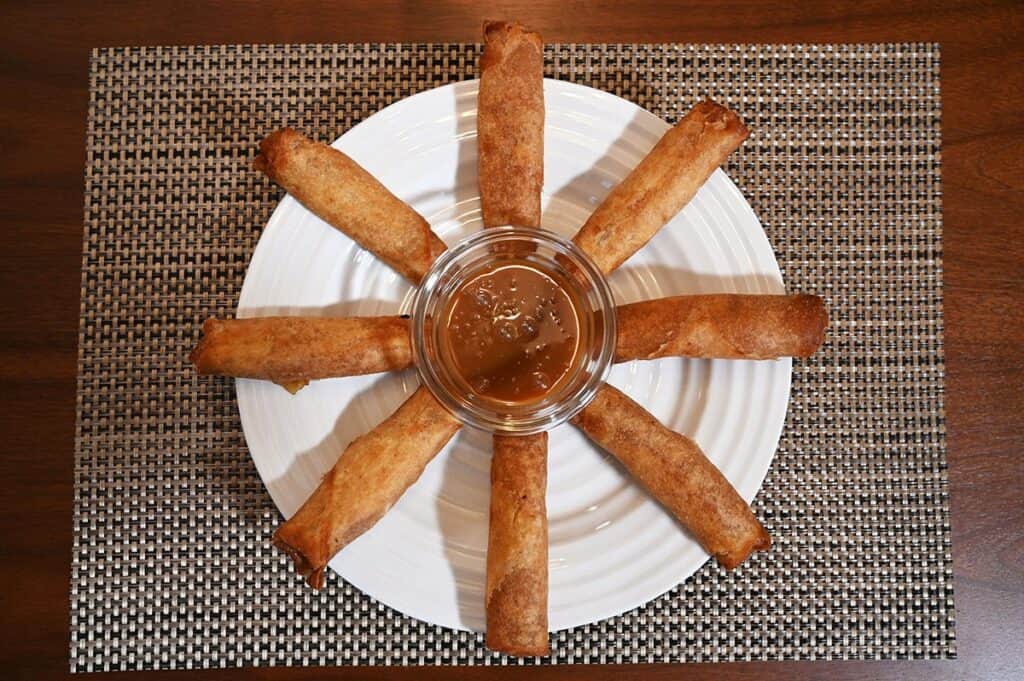 Costco Summ! Apple Pie Rolls baked in the oven and served on a white plate with caramel sauce in the middle.