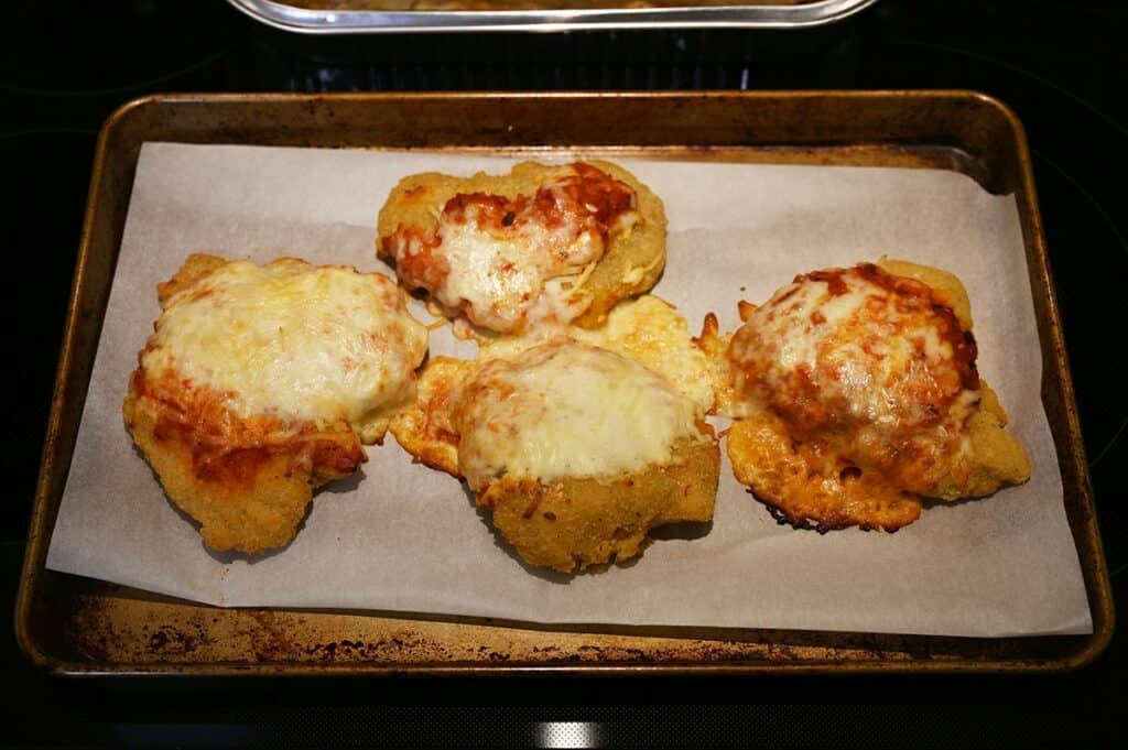 Costco Kirkland Signature Chicken Parmigiana on Cheese Lasagna chicken cooking in the oven on a tray