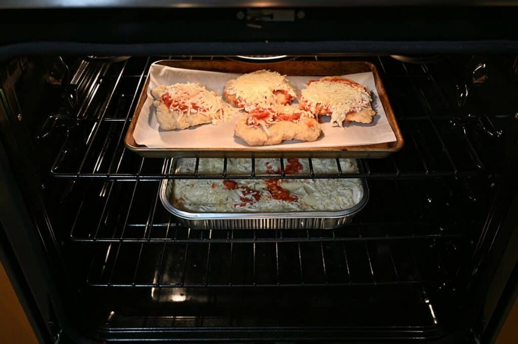 Costco Kirkland Signature Chicken Parmigiana on Cheese Lasagna cooking in the oven on separate racks. 