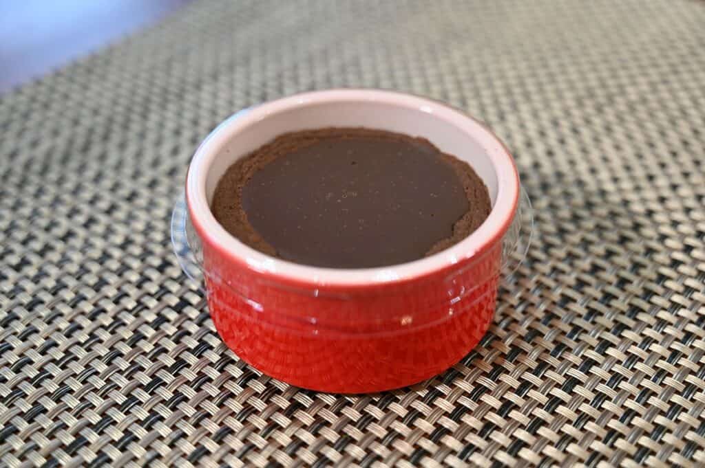 One Costco Delici Belgian Chocolate Soufflé sitting on a table with the plastic lid on, not heated. 