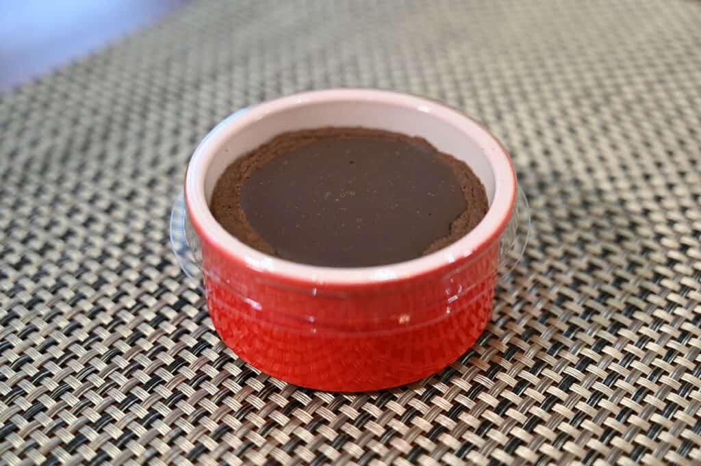 One Costco Delici Belgian Chocolate Soufflé sitting on a table with the plastic lid on, not heated. 