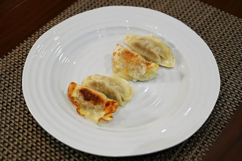 Costco Summ! Sesame Ginger Chicken Gyoza Dumplings cooked and served on a white plate, side image. 
