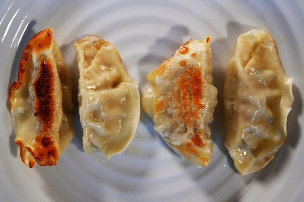 Costco Summ! Sesame Ginger Chicken Gyoza Dumplings cooked and served on a white plate, closeup image. 