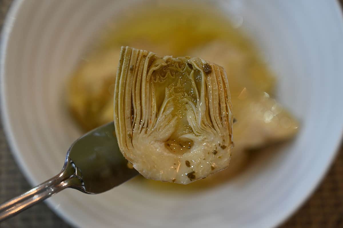 Close up image of the center of one artichoke heart on a fork. 