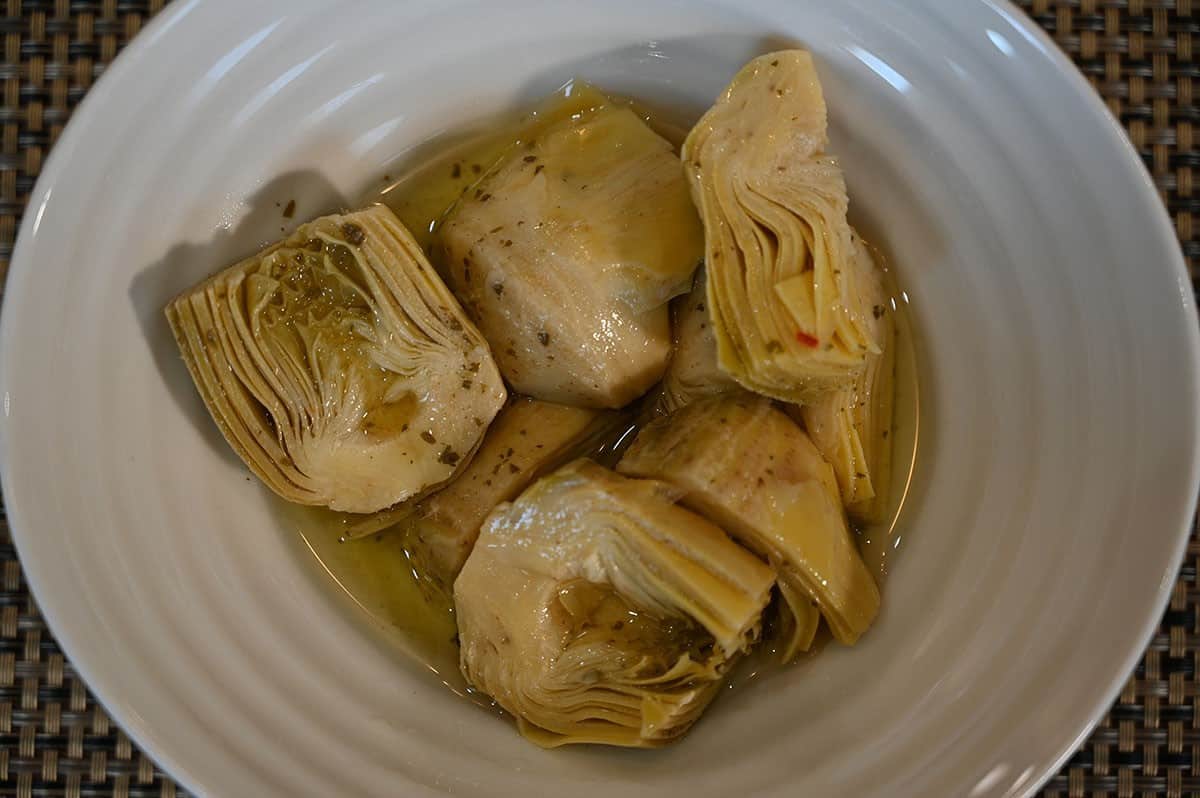 Artichoke hearts served in a white bowl, close up image. 