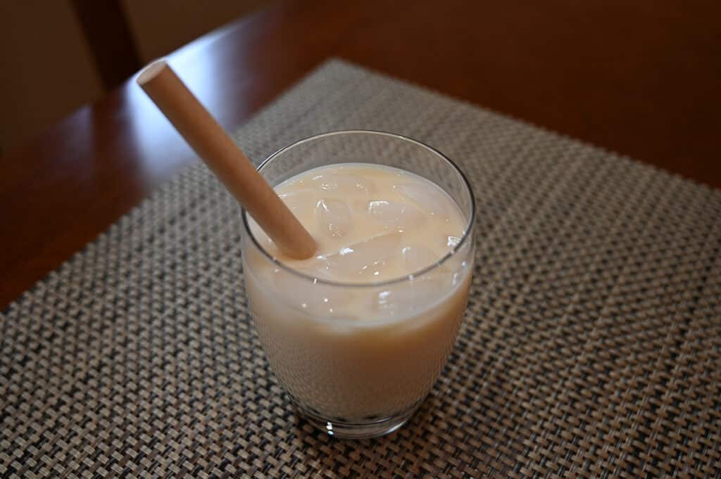 Top down image of the mango boba prepared in a glass with lots of ice in it and a paper straw. The glass is sitting on a table.