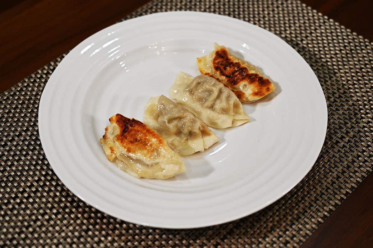 Four Pork & Shiitake Gyoza Dumplings cooked and served on a white plate.  