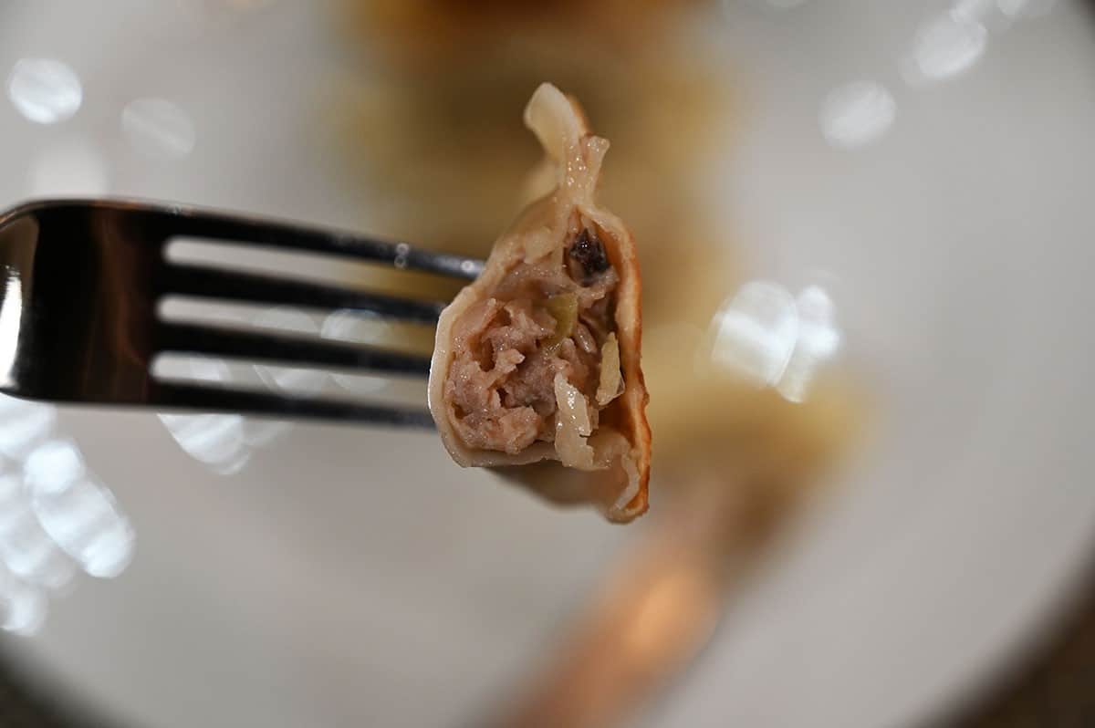 Close up image of one Costco Summ! Pork & Shiitake Gyoza Dumpling with a bite taken out so you can see the filling.  