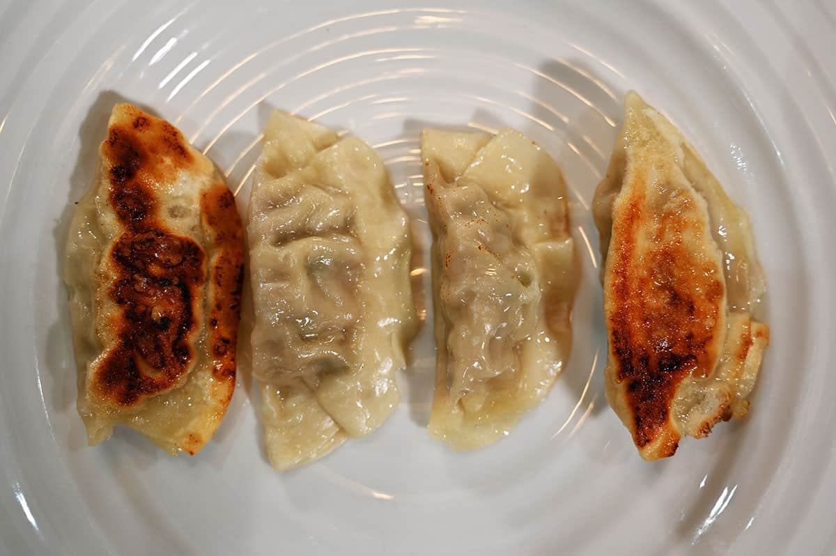 Close up image of four Summ! Pork & Shiitake Gyoza Dumplings cooked and on a white plate.