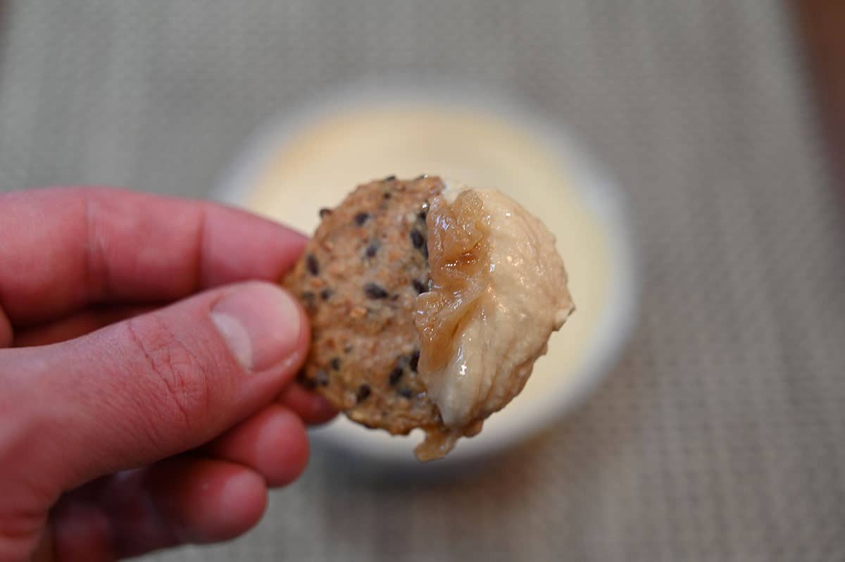 Closeup image of a cracker with caramelized onion hummus on it. 