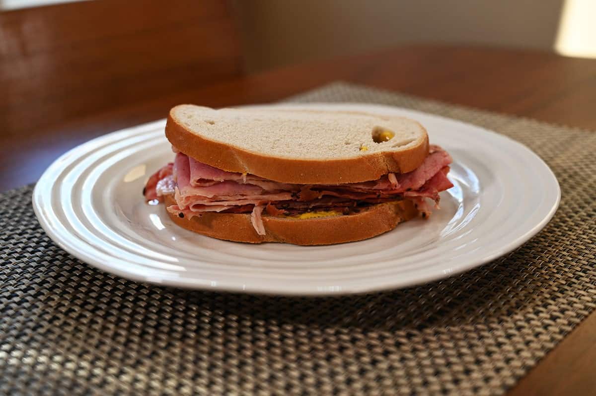Costco Schwartz's Smoked Meat made into a sandwich using rye bread on a white plate. 