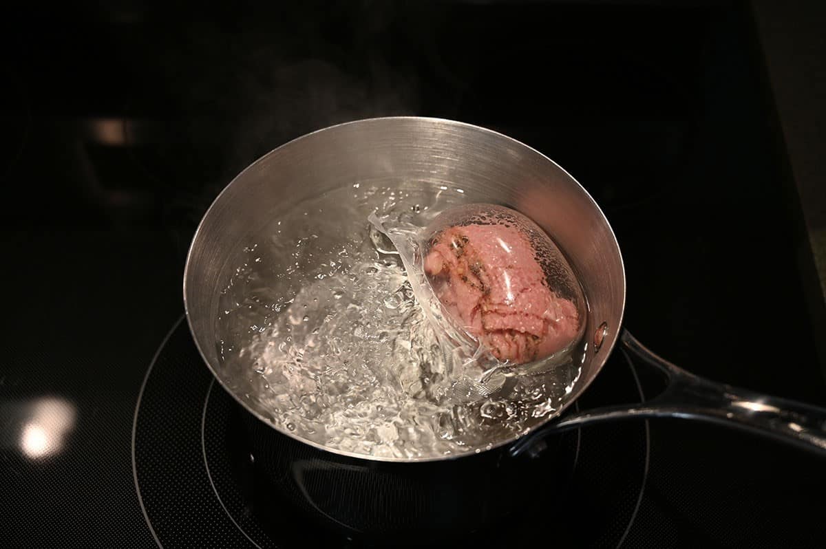 Image showing one pack of Costco Schwartz's Smoked Meat in a pot of boiling water. 