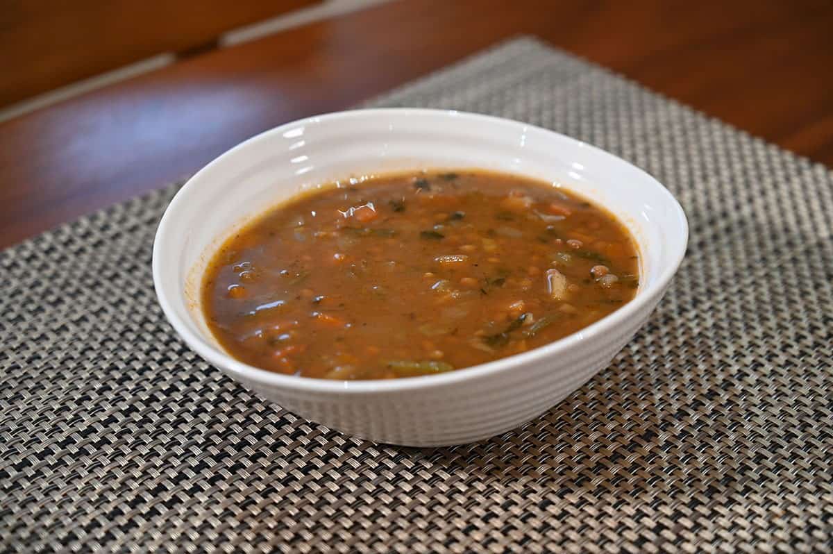Lentil soup heated and served in a  white bowl, side view. 