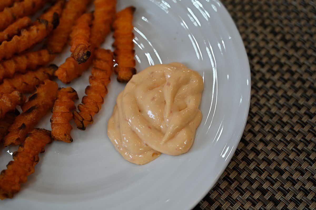 Close up image of Costco Jalapeno Lime Aioli  on a plate beside sweet potato fries. 