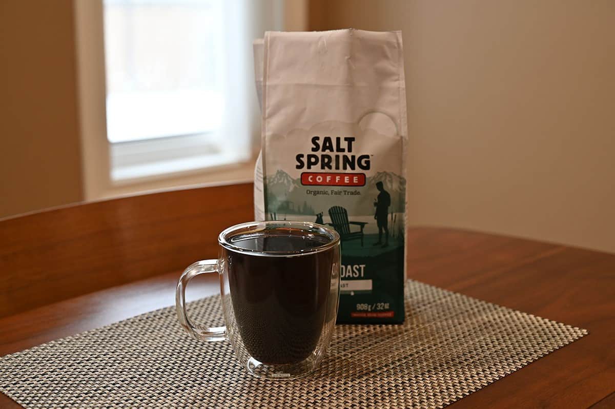 Costco Salt Spring Coffee beans bag sitting on a table with a brewed cup of coffee in front of it. 