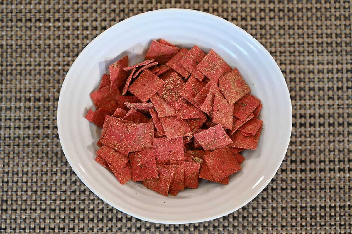 Purple carrot crackers poured into a white bowl. Top down image. 