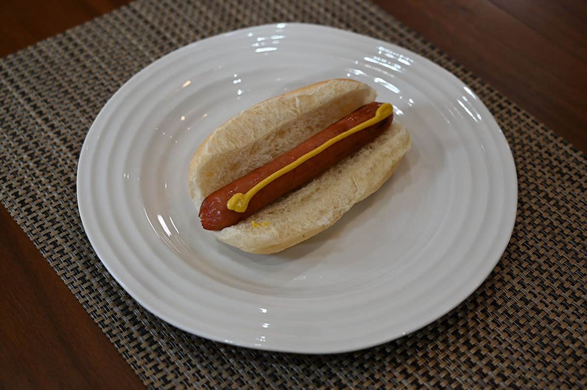 One Costco Siwin Japanese Style Sausage served in a bun with mustard like a hot dog. 