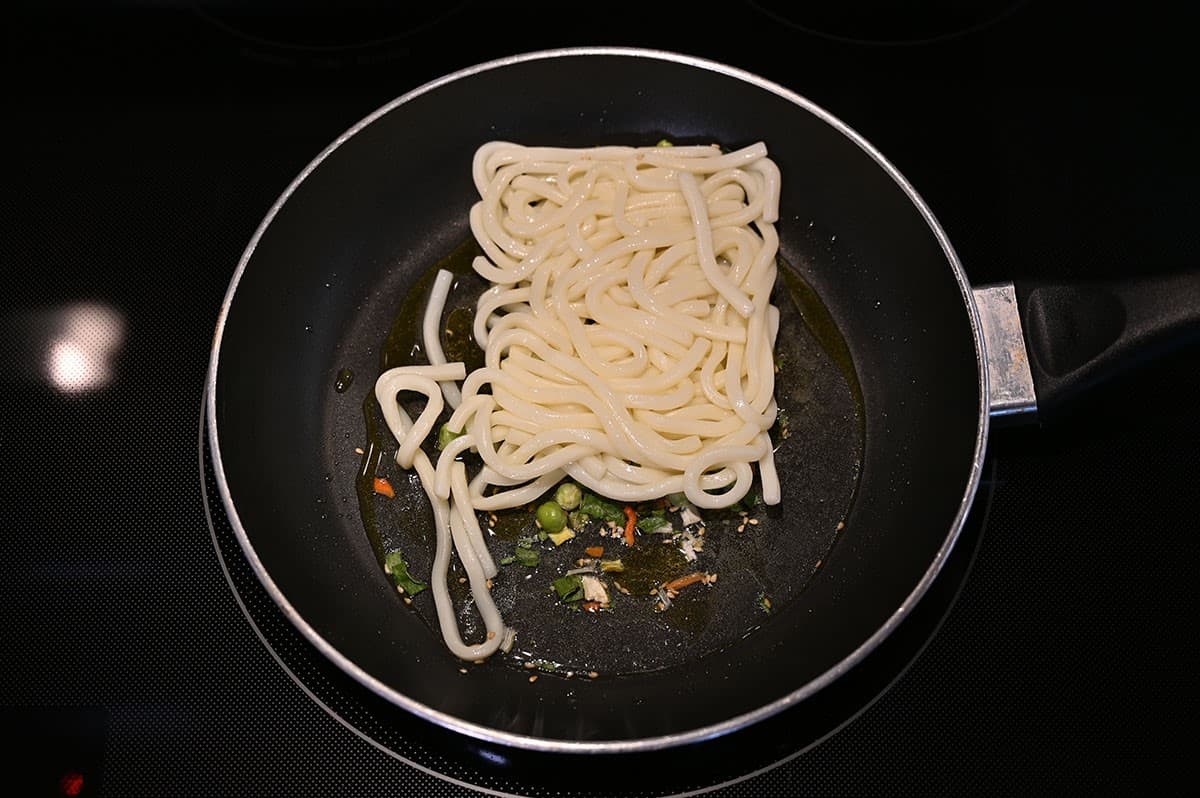 Stir-fry noodles and vegetables in a frying pan with oil, top down image. 