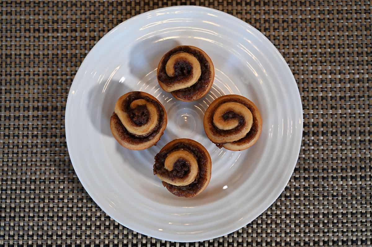 Four Costco Universal Bakery Petite Cinnamon Rolls on a white plate, top down image. 