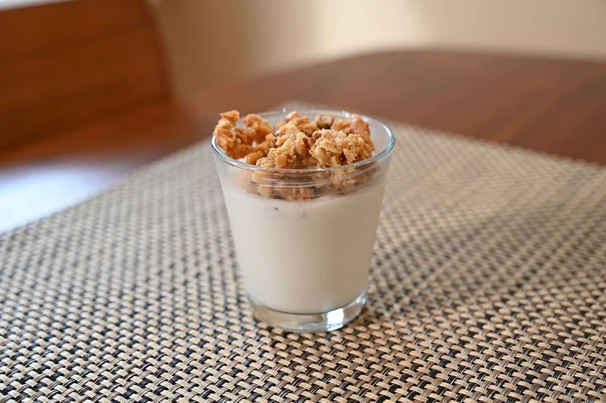 Image of Costco granola being used as a topping on yogurt, yogurt cup sitting on a table. , 
