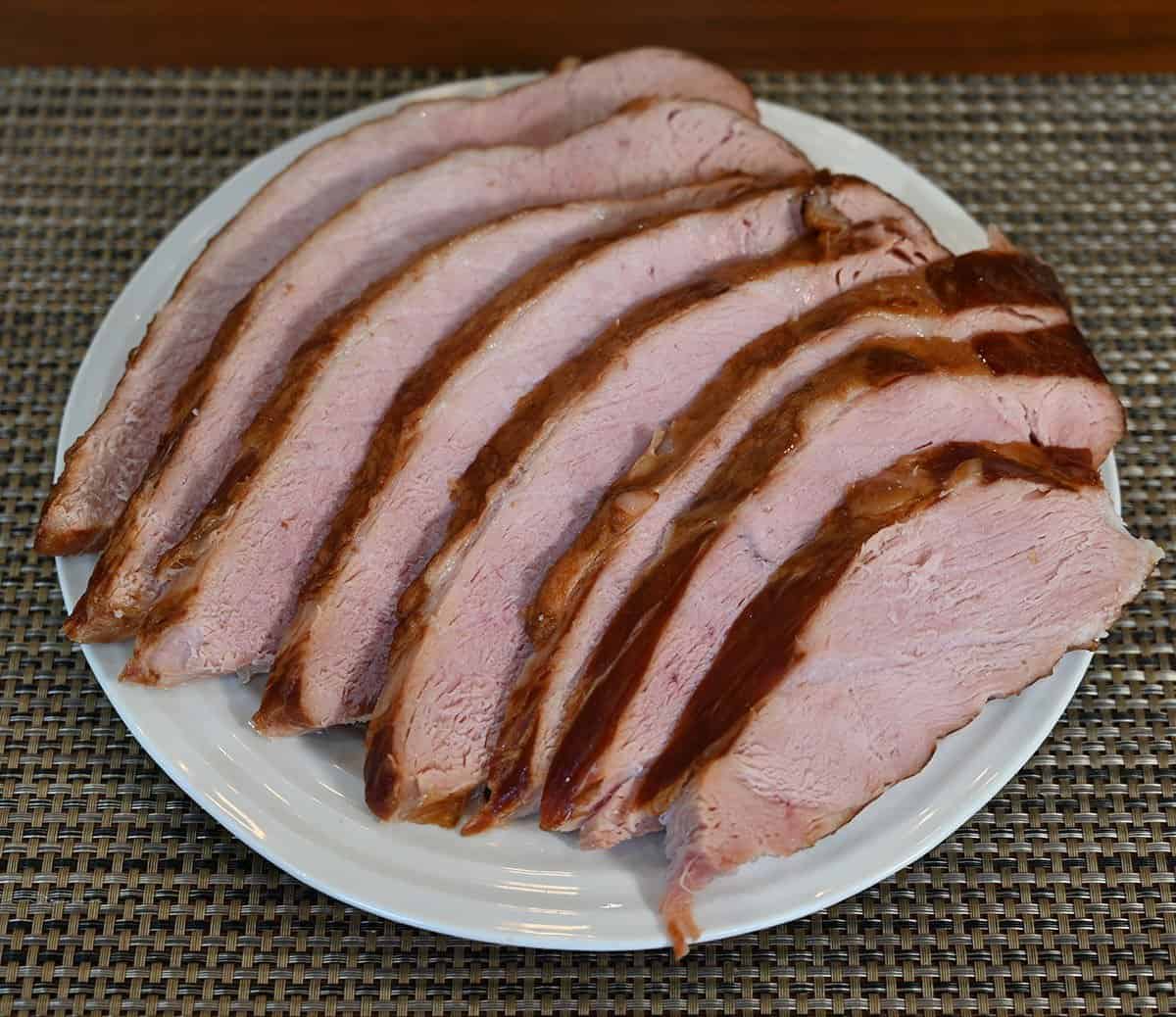 Slices of Costco Kirkland Signature Master Carve Ham cooked and served on a white plate. 