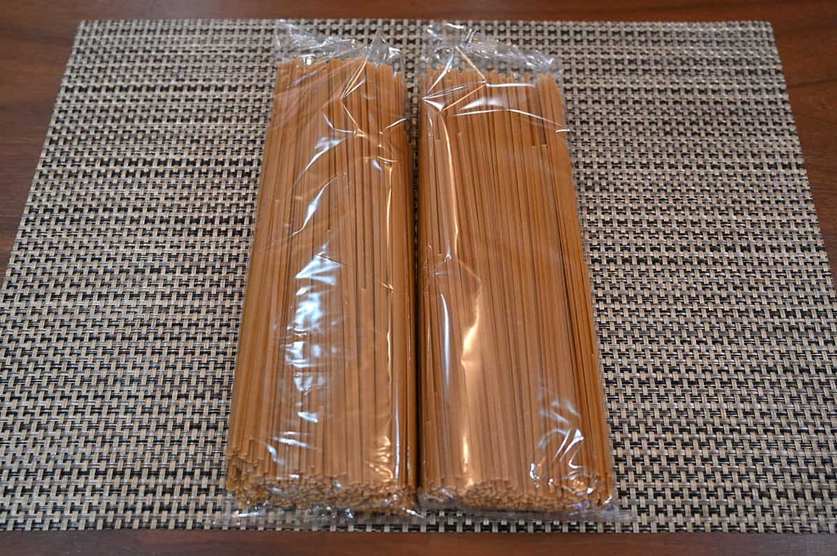 Image of two separate bags of uncooked linguini sitting on a table. 
