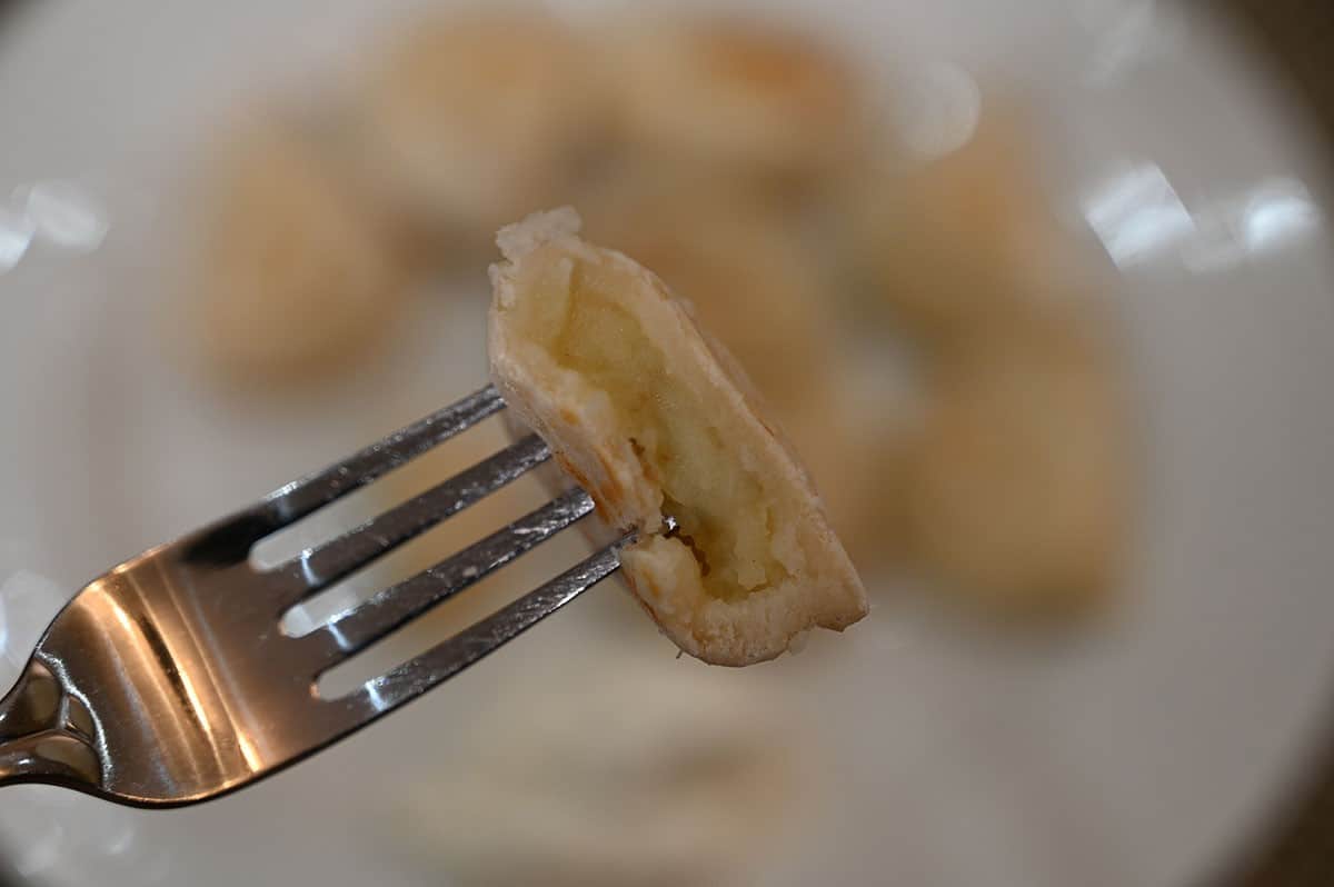 Picture of one perogy with a  bite taken out of it, close up image. 