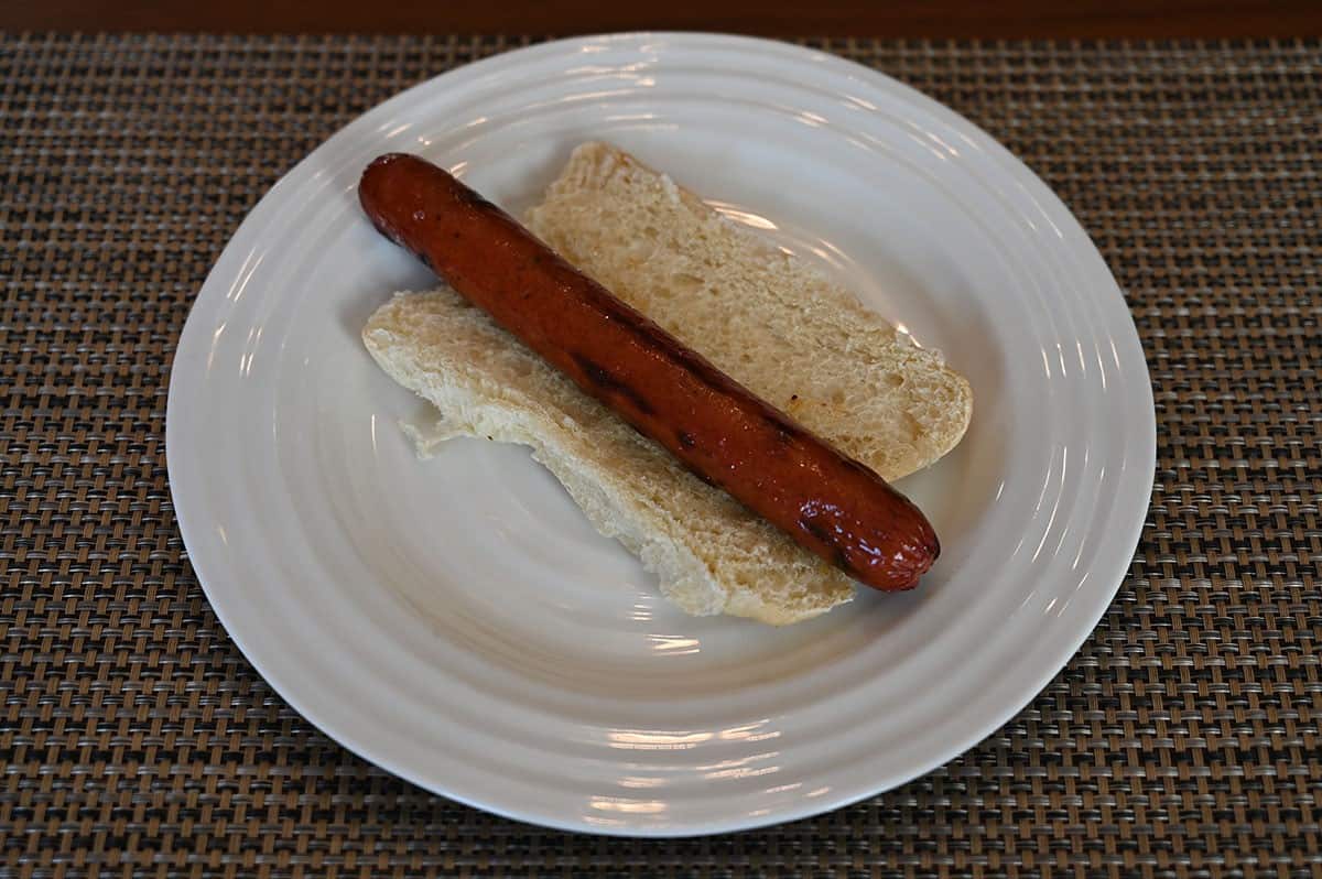 Costco Kirkland Signature Beef Polish Sausage on a bun with the bun open, served on a white plate. 