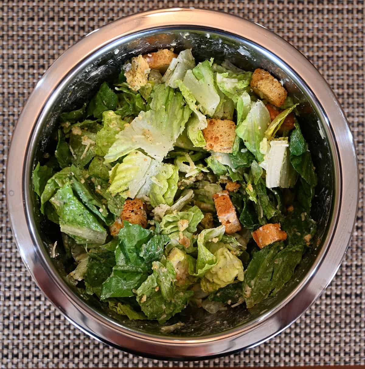 Costco Taylor Farms Ultimate Caesar Salad Kit prepared in a large metal bowl, top down image. 
